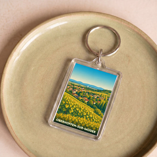 Porte-clés souvenir de la ville d'Oberhoffen-sur-Moder avec une illustration stylisée de vignobles et du village.
