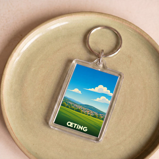 Porte-clés souvenir de la ville de Œting avec une illustration stylisée d'un paysage verdoyant.