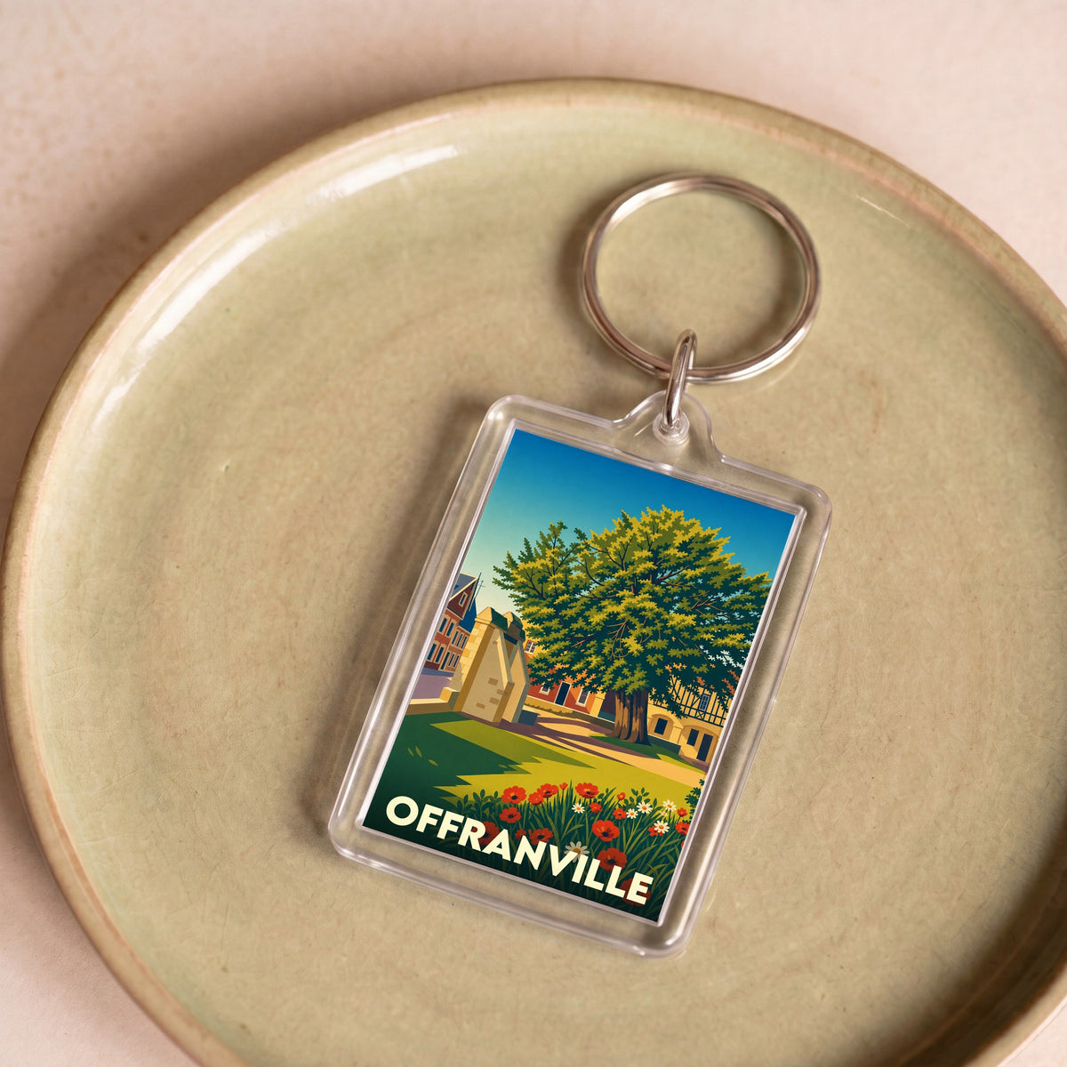Porte-clés souvenir de la ville d'Offranville avec une illustration stylisée d'un paysage local.