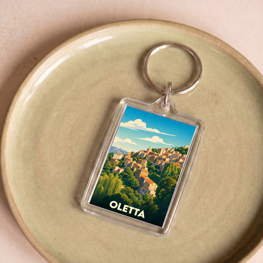 Porte-clés souvenir de la ville de Oletta avec une illustration stylisée d'un village perché.
