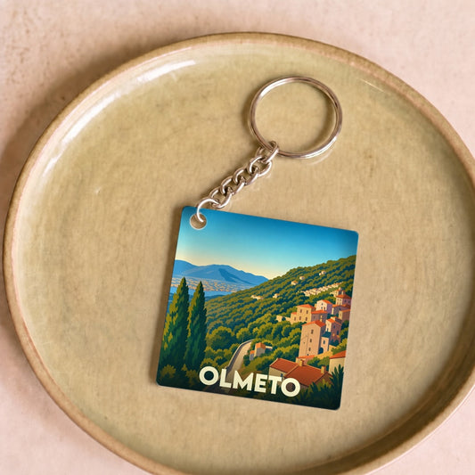 Porte-clés souvenir de la ville de Olmeto avec une illustration stylisée d'un paysage corse.