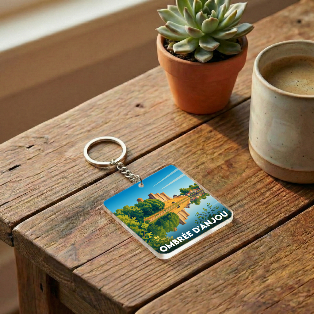 Porte-clés souvenir de la ville de Ombrée d'Anjou avec une illustration paysagère stylisée.