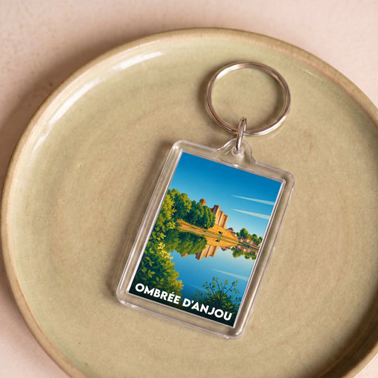 Porte-clés souvenir de la ville de Ombrée d'Anjou avec une illustration paysagère stylisée.
