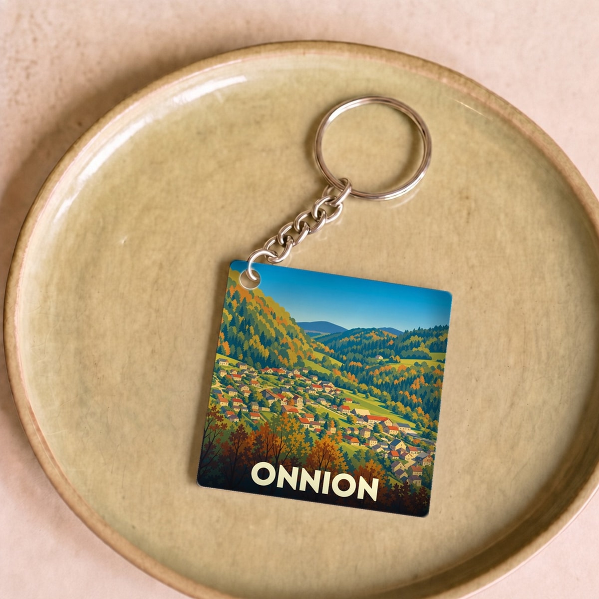Porte-clés souvenir de la ville d'Onnion avec une illustration stylisée de paysages montagneux en automne.