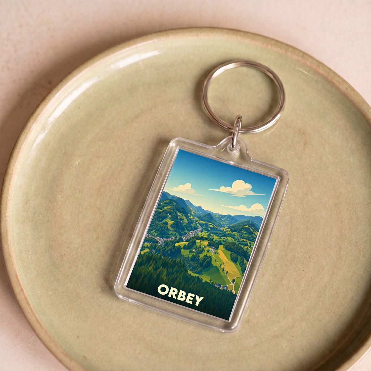 Porte-clés souvenir de la ville d'Orbey présentant une illustration stylisée de son paysage montagneux.