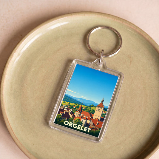 Porte-clés souvenir de la ville d'Orgelet avec une illustration stylisée de son clocher et du paysage environnant.