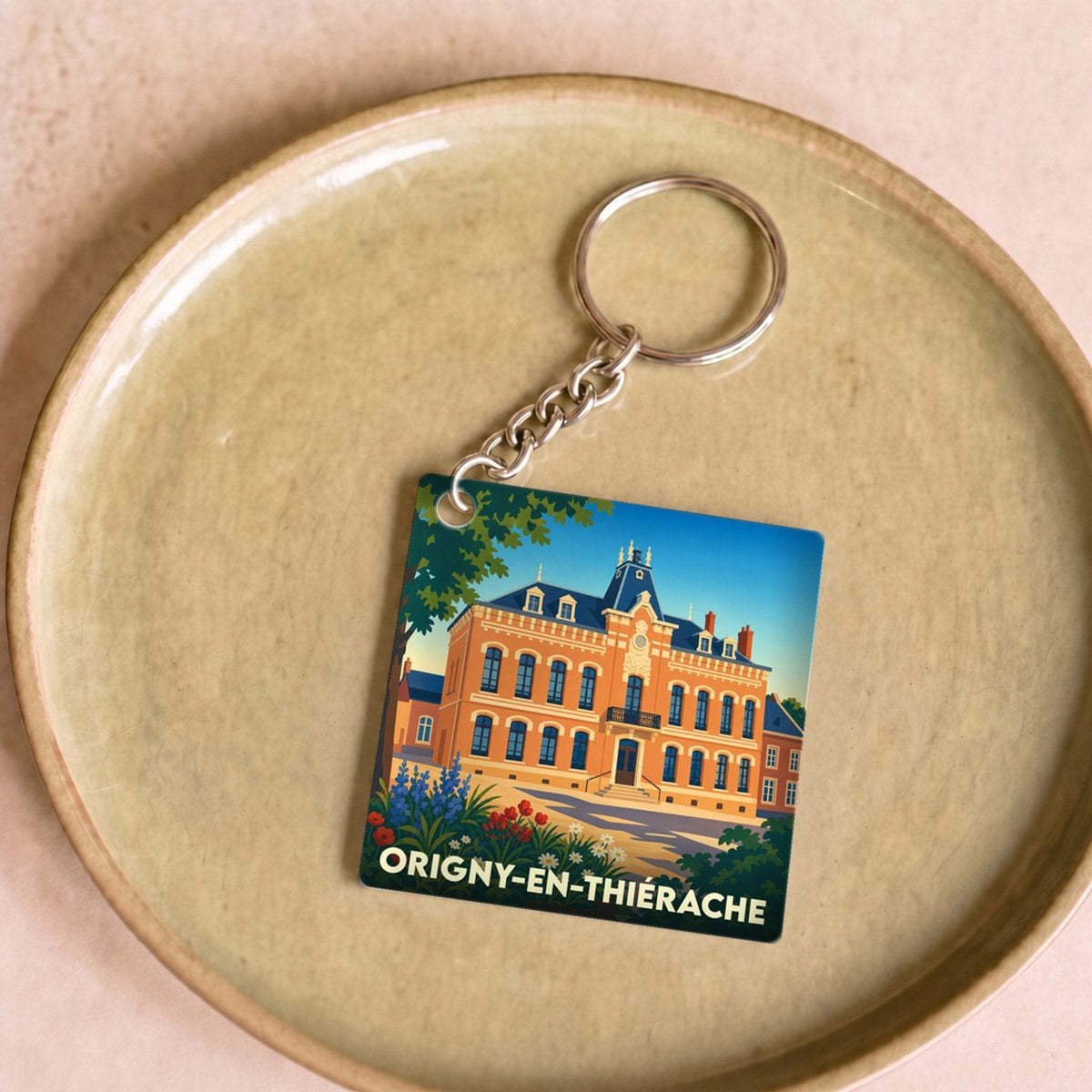 Porte-clés souvenir de la ville d'Origny-en-Thiérache avec une illustration stylisée de son hôtel de ville.