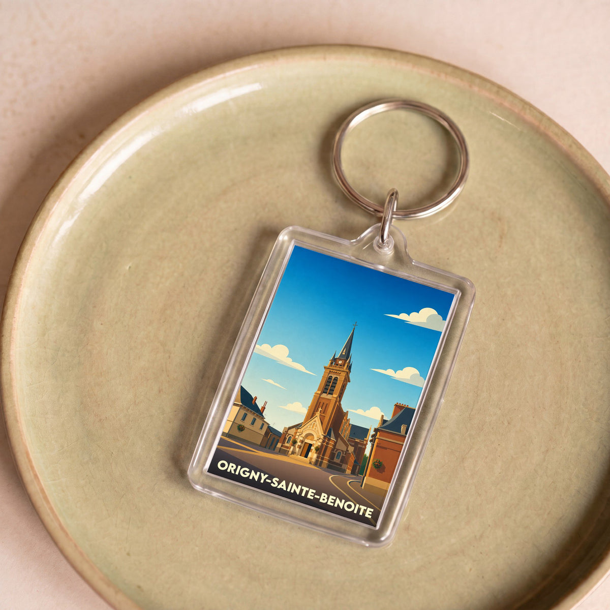 Porte-clés souvenir de la ville d'Origny-Sainte-Benoite avec une illustration stylisée de son église.