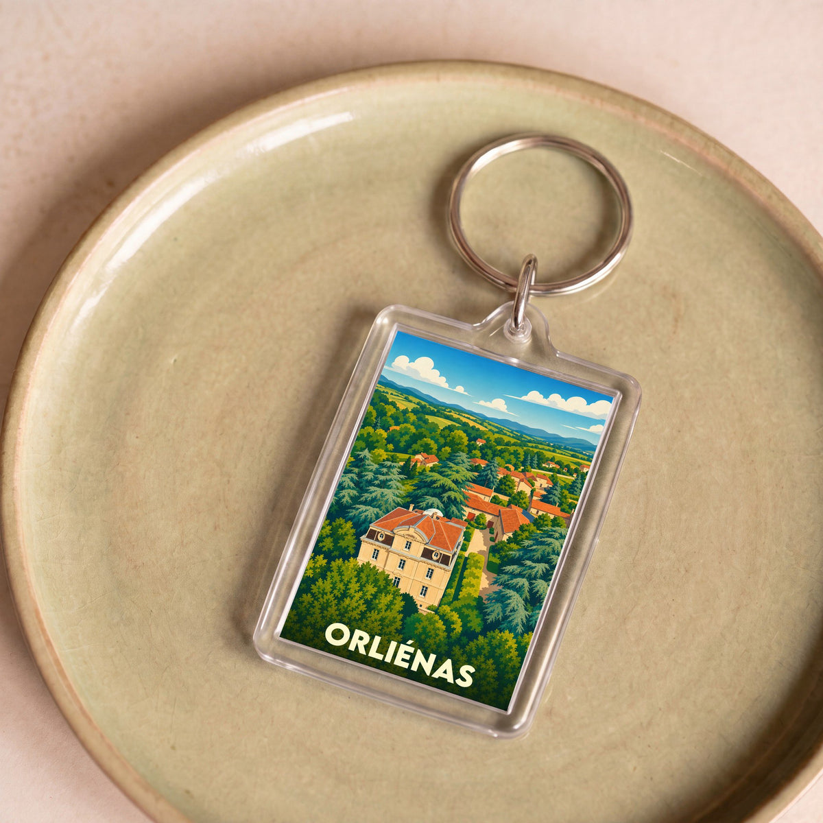 Porte-clés souvenir de la ville d'Orliénas avec une illustration stylisée de son paysage.