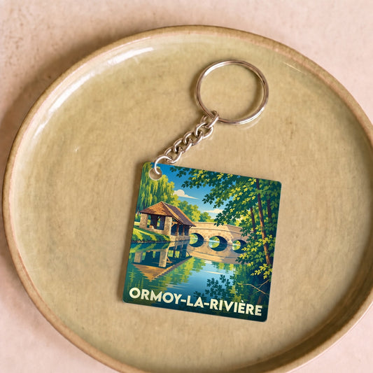 Porte-clés souvenir de la ville de Ormoy-la-Rivière avec une illustration stylisée de son patrimoine au bord de l'eau.