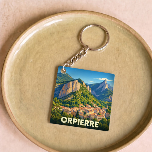 Porte-clés souvenir de la ville d'Orpierre avec une illustration stylisée de son village et de ses falaises.