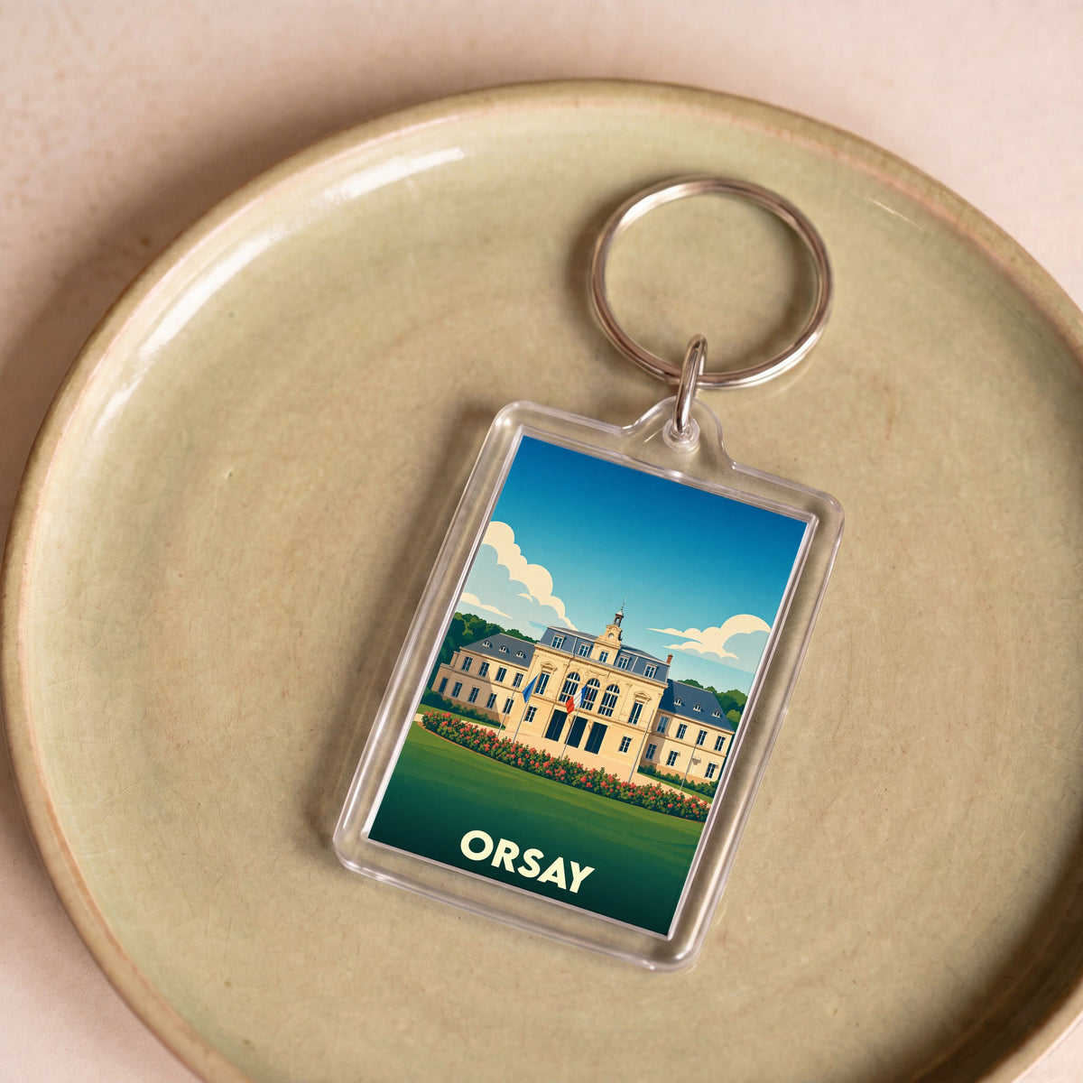 Porte-clés souvenir de la ville de Orsay avec une illustration stylisée d'un bâtiment historique.