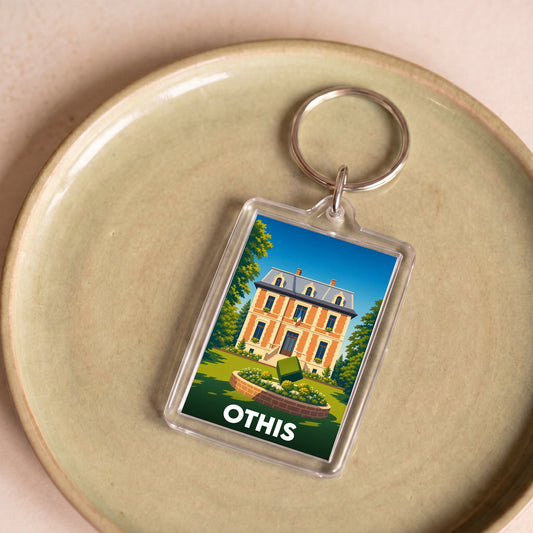 Porte-clés souvenir de la ville d'Othis avec une illustration stylisée d'une demeure bourgeoise.