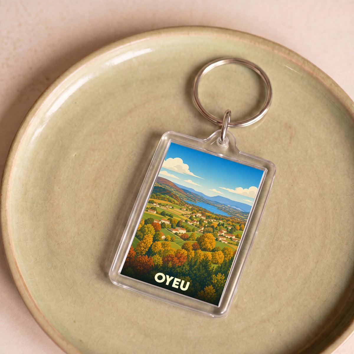 Porte-clés souvenir de la ville d'Oyeu avec une illustration stylisée d'un paysage d'automne.