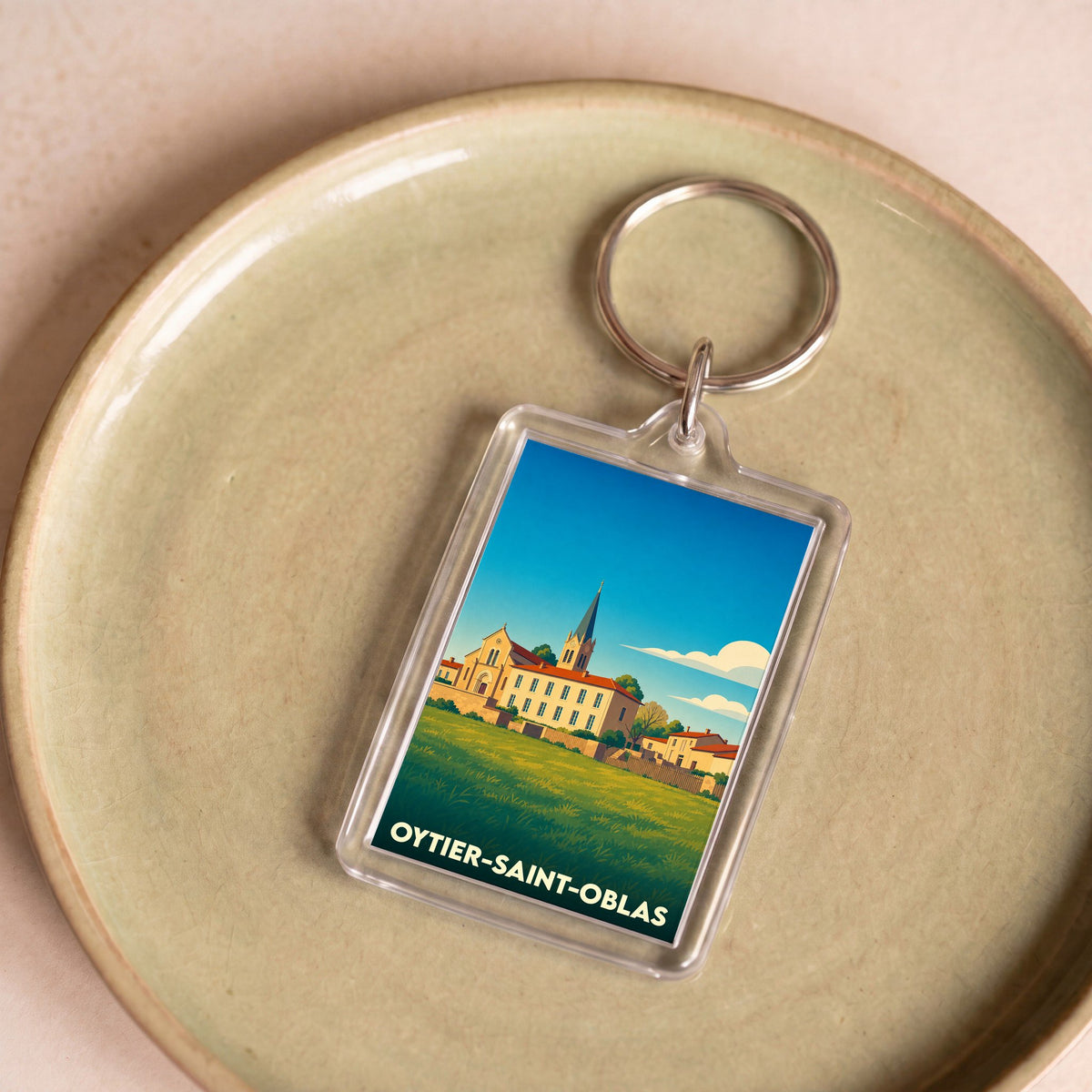 Porte-clés souvenir de la ville de Oytier-Saint-Oblas avec une illustration stylisée d'un paysage urbain.