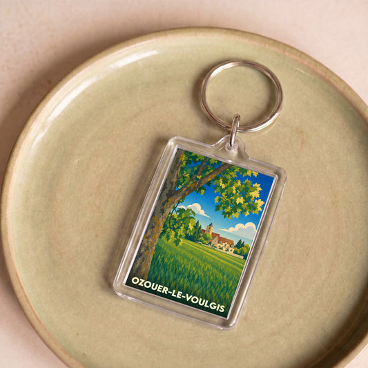 Porte-clés souvenir de la ville d'Ozouer-le-Voulgis avec une illustration de paysage champêtre.