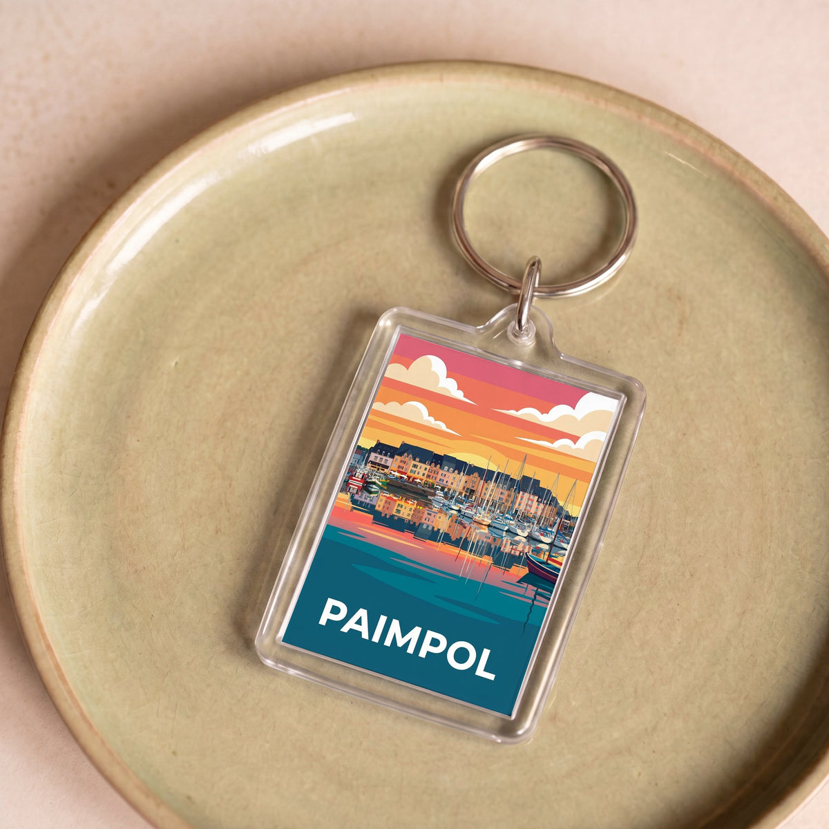 Porte-clés souvenir de la ville de Paimpol avec une illustration stylisée de son port au coucher du soleil.