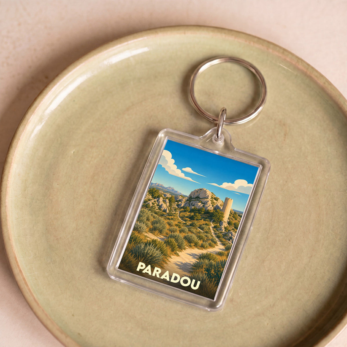 Porte-clés souvenir de la ville de Paradou avec une illustration stylisée d'un paysage provençal.