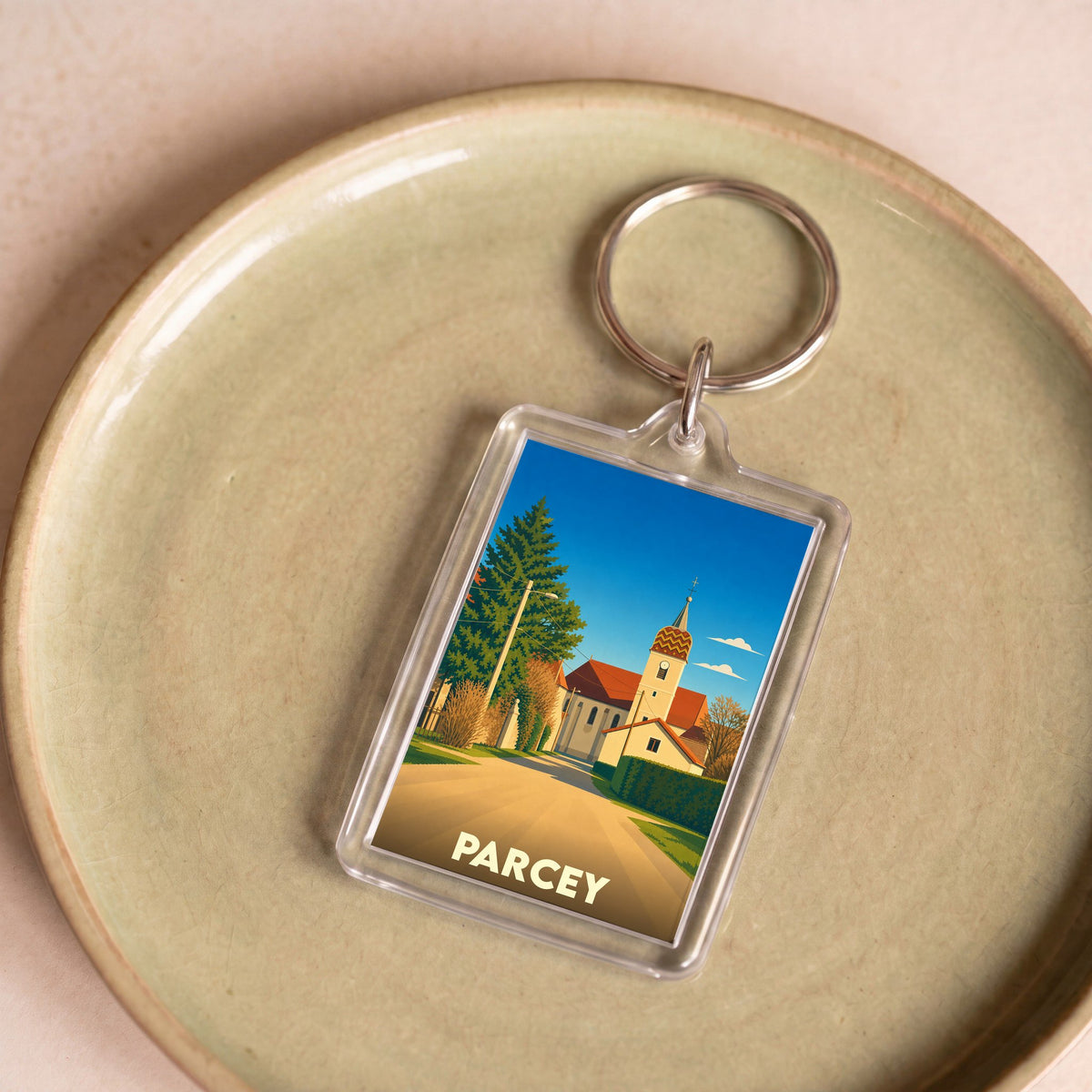 Porte-clés souvenir de la ville de Parcey avec une illustration stylisée d'une église et son clocher.