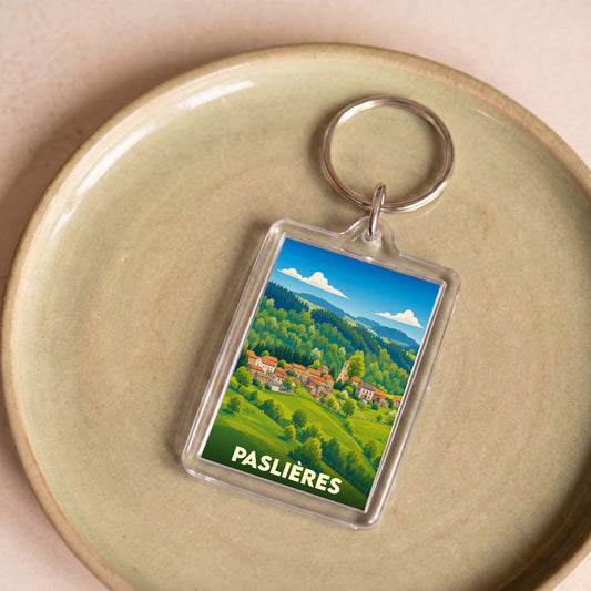 Porte-clés souvenir de la ville de Paslières avec une illustration stylisée de son paysage vallonné.