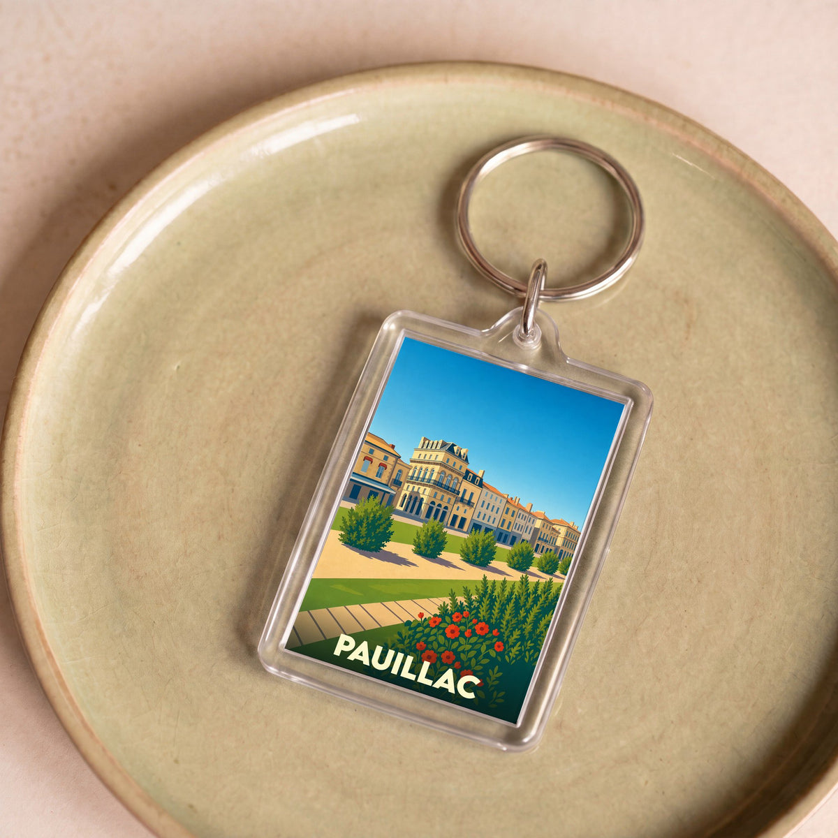 Porte-clés souvenir de la ville de Pauillac avec une illustration stylisée et colorée.