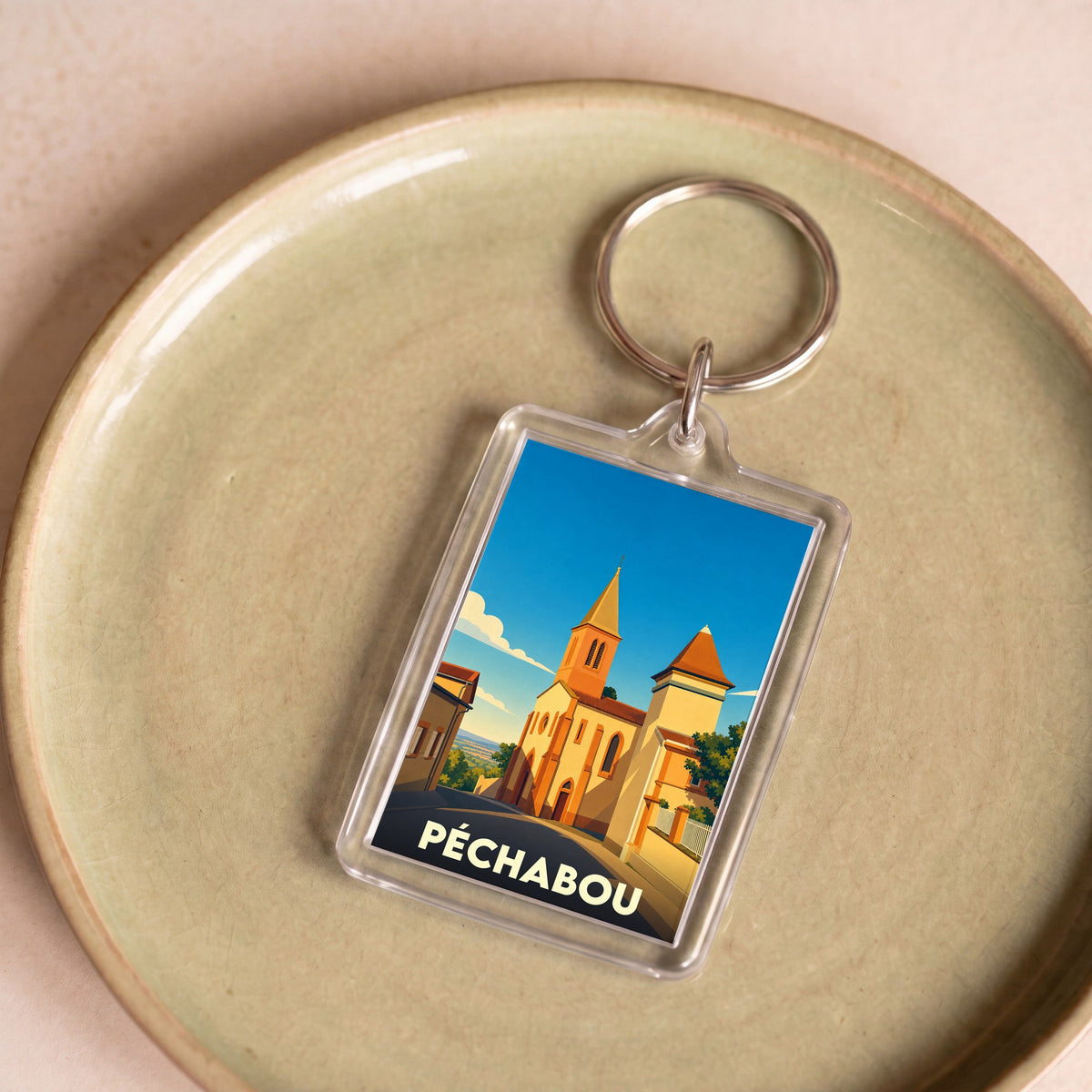 Porte-clés souvenir de la ville de Péchabou avec une illustration stylisée de son église.