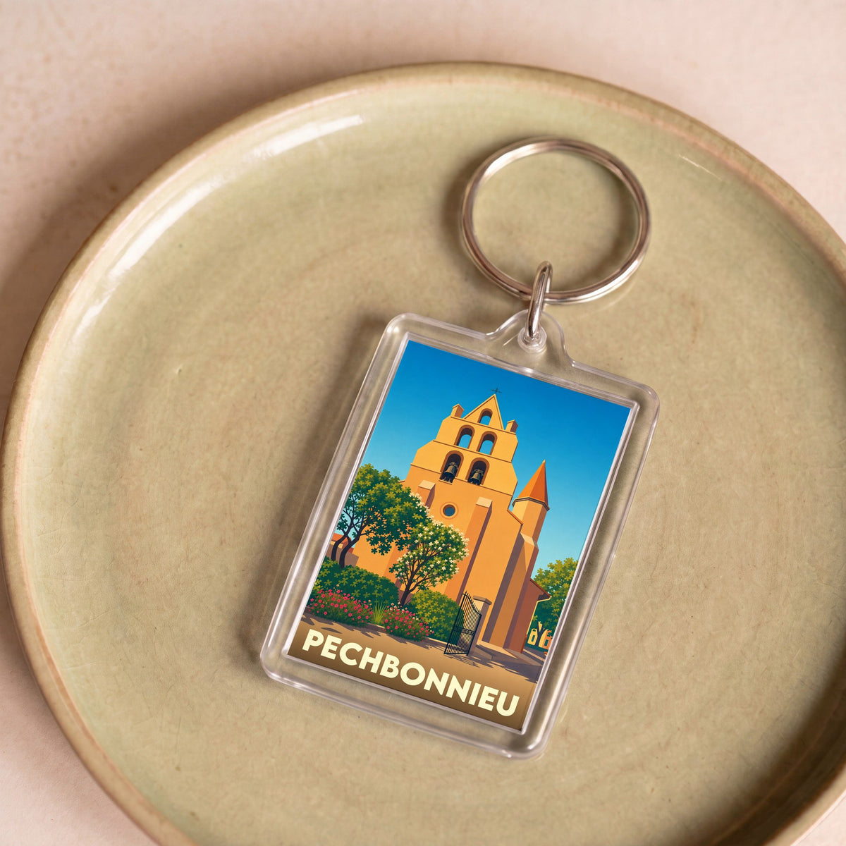 Porte-clés souvenir de la ville de Pechbonnieu avec une illustration stylisée de son église.
