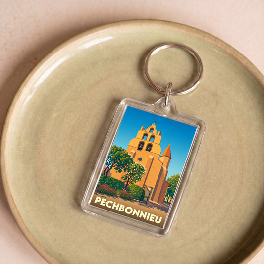 Porte-clés souvenir de la ville de Pechbonnieu avec une illustration stylisée de son église.