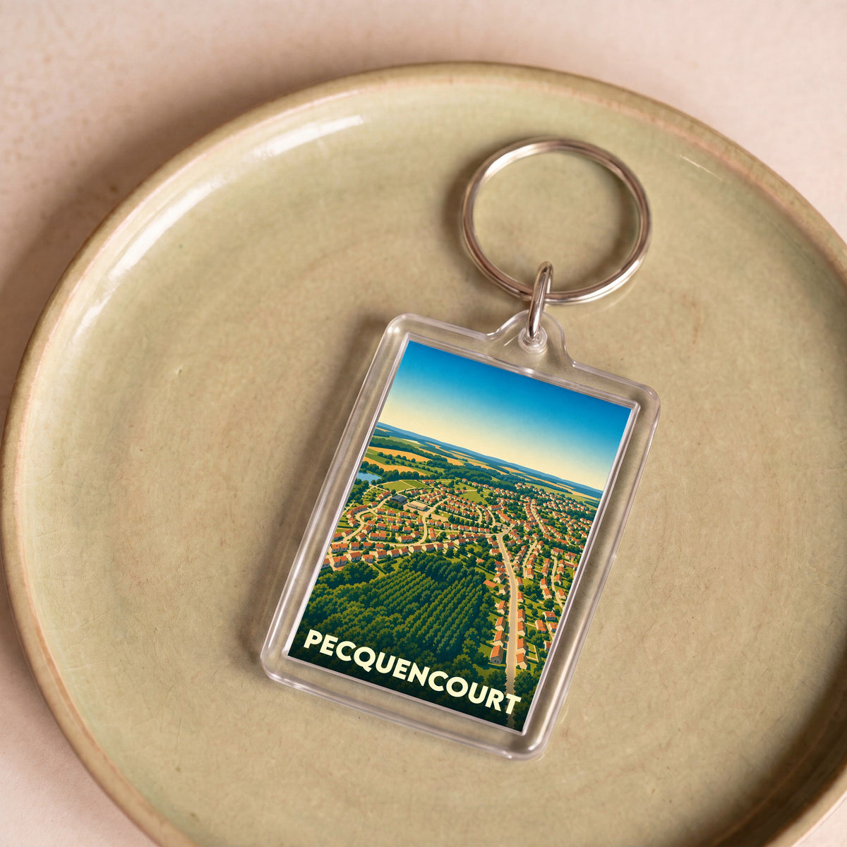 Porte-clés souvenir de la ville de Pecquencourt avec une illustration aérienne stylisée.