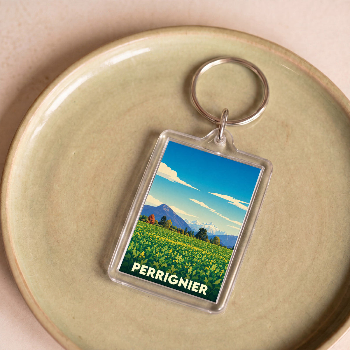 Porte-clés souvenir de la ville de Perrignier avec une illustration stylisée de paysages montagneux.