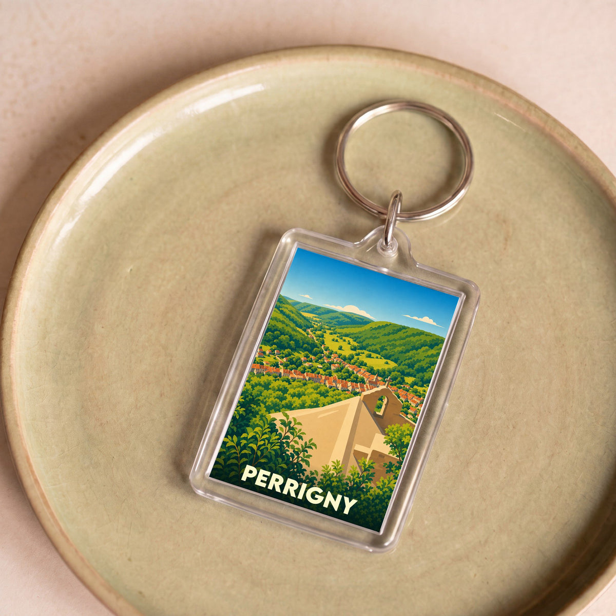 Porte-clés souvenir de la ville de Perrigny avec une illustration stylisée d'un paysage de vallée.