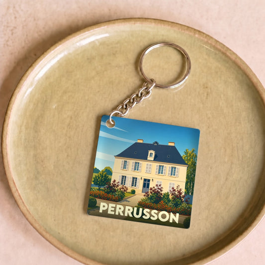 Porte-clés souvenir de la ville de Perrusson avec une illustration stylisée d'une demeure bourgeoise.