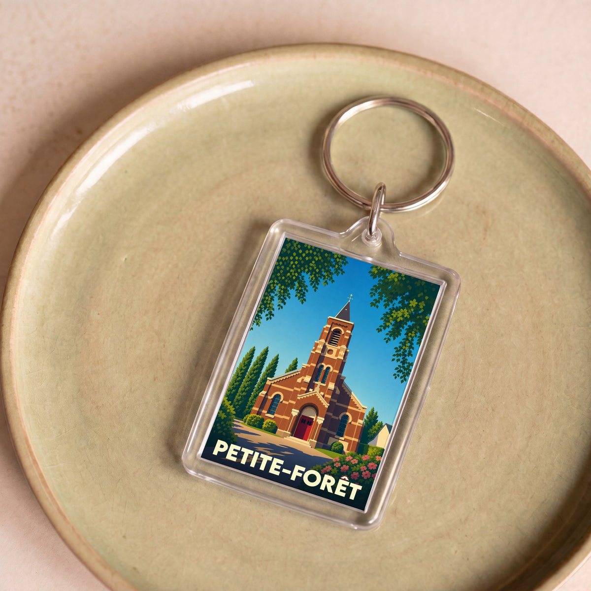 Porte-clés souvenir de la ville de Petite-Forêt avec une illustration stylisée de son église.