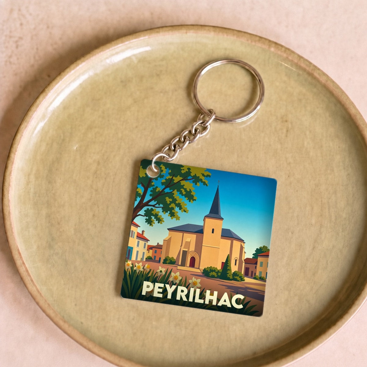 Porte-clés souvenir de la ville de Peyrilhac avec une illustration stylisée de son église.