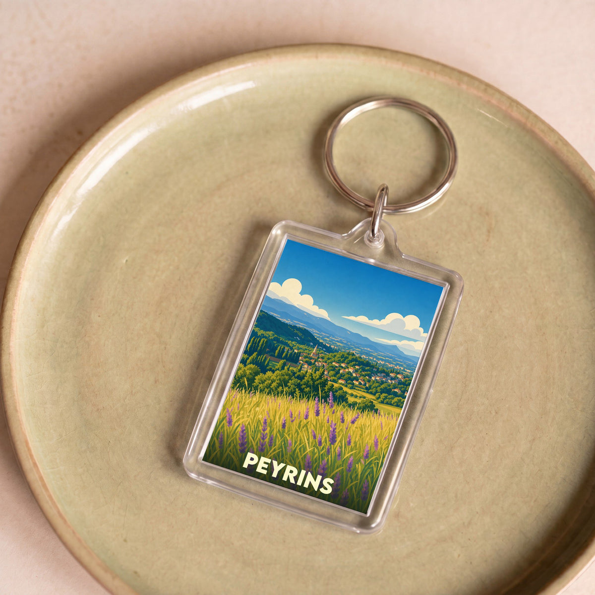 Porte-clés souvenir de la ville de Peyrins avec une illustration stylisée de paysages provençaux.