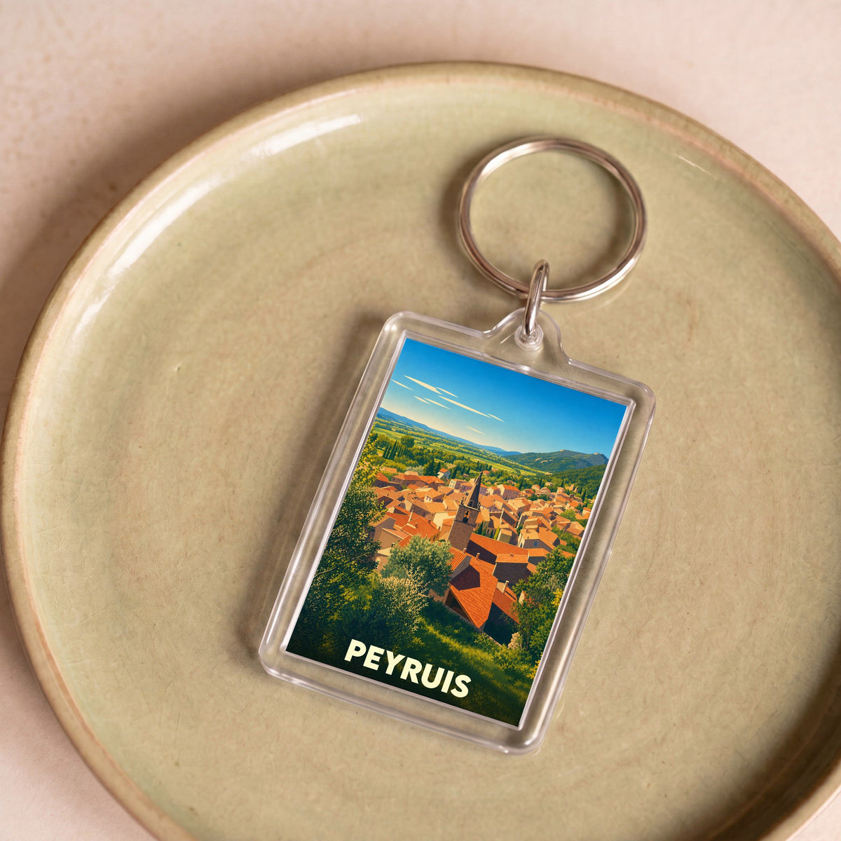 Porte-clés souvenir de la ville de Peyruis avec une illustration stylisée de ses toits provençaux.