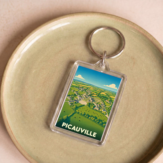 Porte-clés souvenir de la ville de Picauville avec une illustration stylisée de son paysage rural.