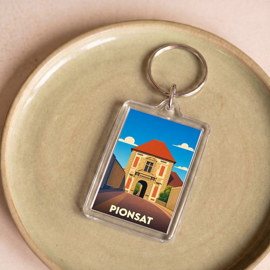 Porte-clés souvenir de la ville de Pionsat avec une illustration stylisée de son patrimoine.