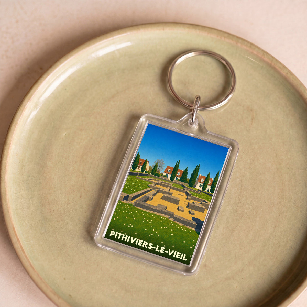 Porte-clés souvenir de la ville de Pithiviers-le-Vieil avec une illustration stylisée de vestiges archéologiques.