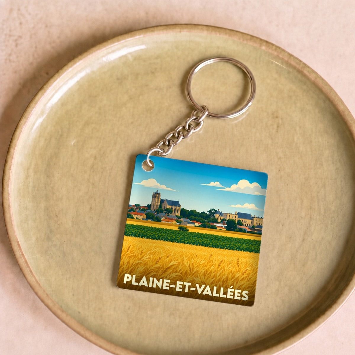 Porte-clés souvenir de la ville de Plaine-et-Vallées avec une illustration stylisée.