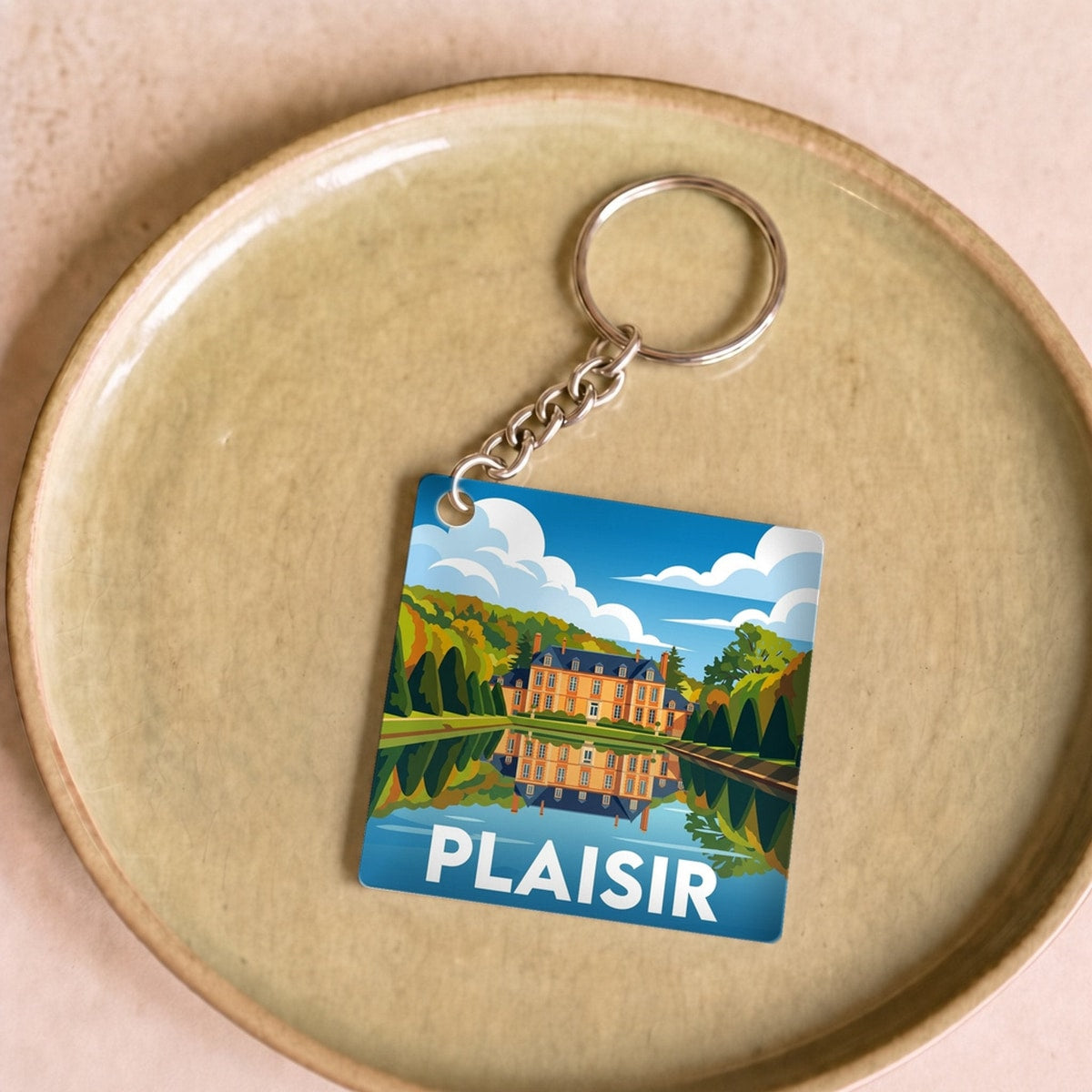 Porte-clés souvenir de la ville de Plaisir avec une illustration stylisée d'un château et de son reflet.