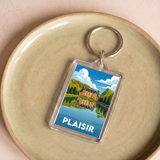 Porte-clés souvenir de la ville de Plaisir avec une illustration stylisée d'un château et de son reflet.