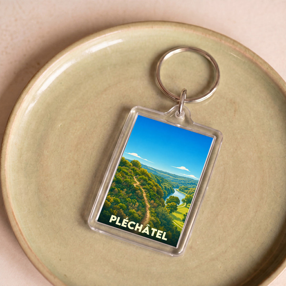 Porte-clés souvenir de la ville de Pléchâtel avec une illustration stylisée de son paysage naturel.