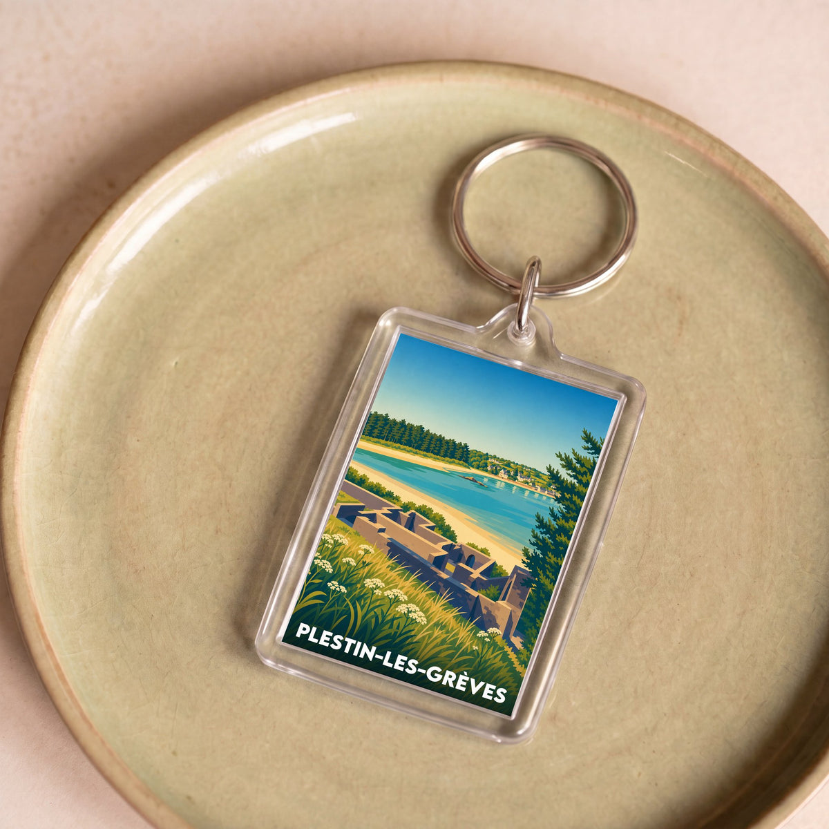 Porte-clés souvenir de la ville de Plestin-les-Grèves avec une illustration stylisée de paysage côtier.