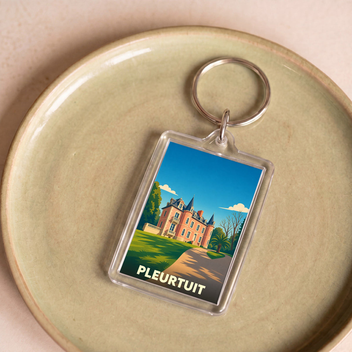 Porte-clés souvenir de la ville de Pleurtuit avec une illustration stylisée d'un manoir.