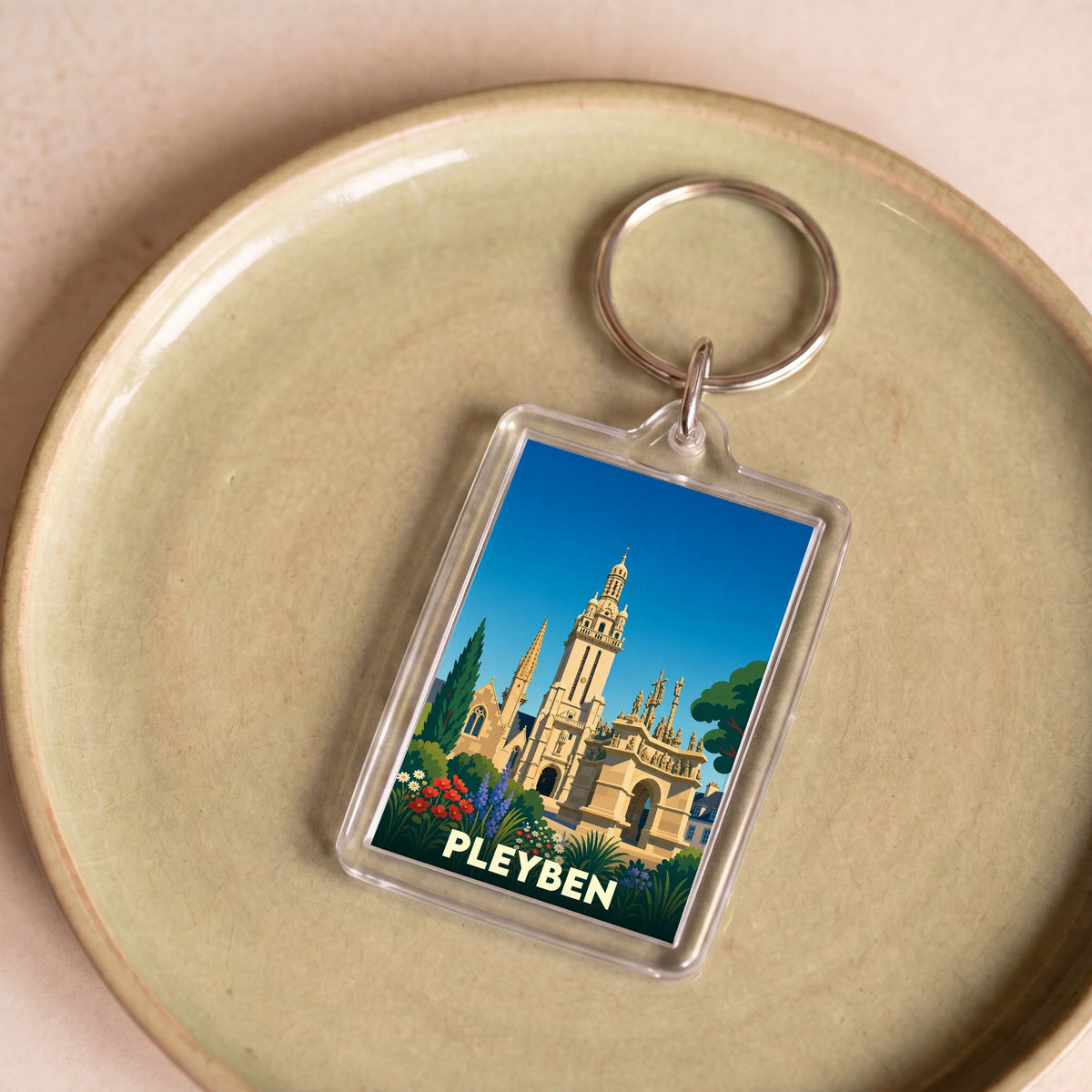 Porte-clés souvenir de la ville de Pleyben avec une illustration stylisée de son enclos paroissial.