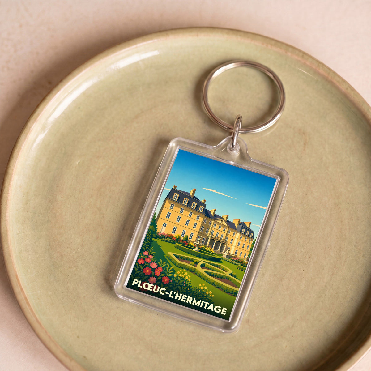 Porte-clés souvenir de la ville de Plœuc-L'Hermitage avec une illustration stylisée d'un château.