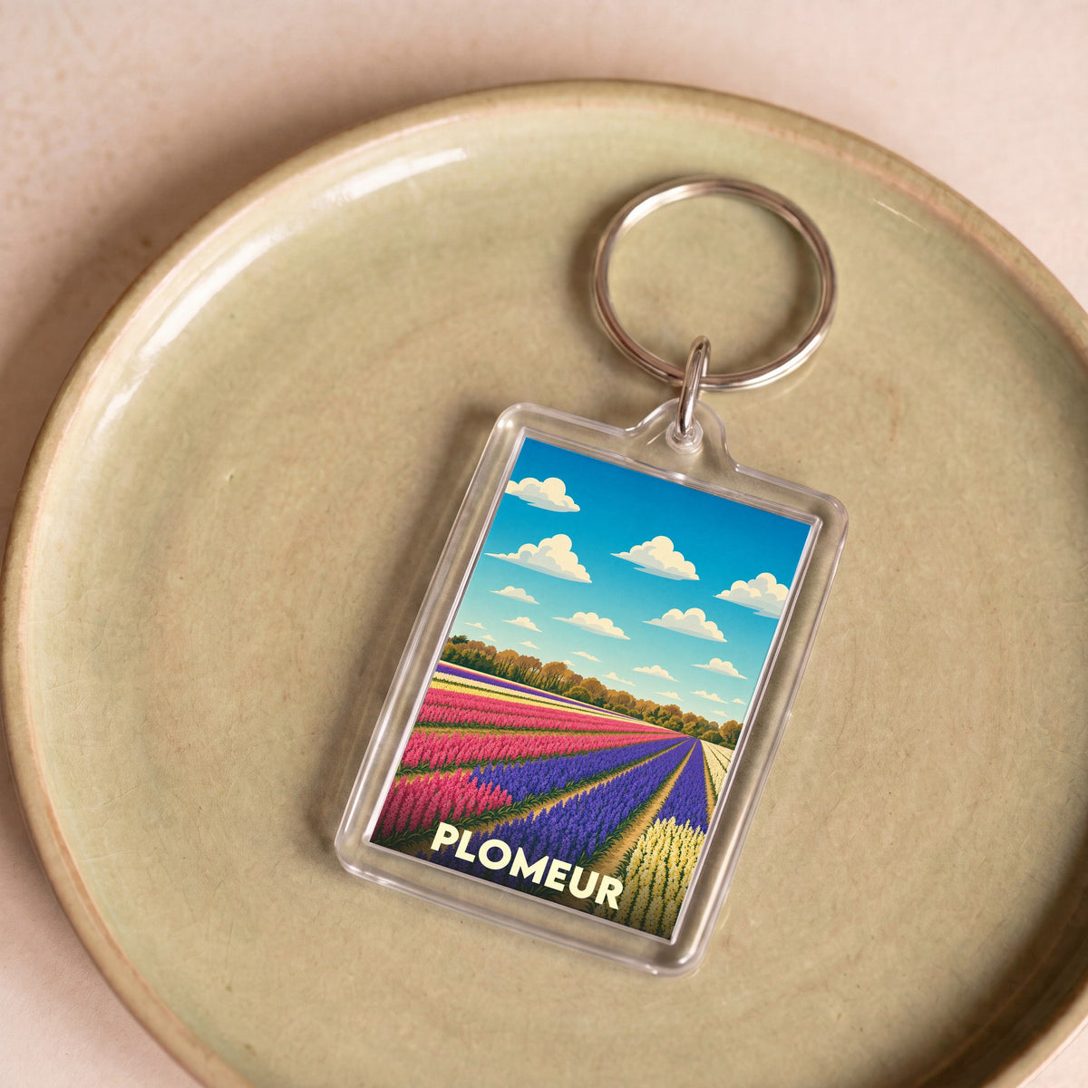 Porte-clés souvenir de la ville de Plomeur avec une illustration stylisée de champs de fleurs colorés.