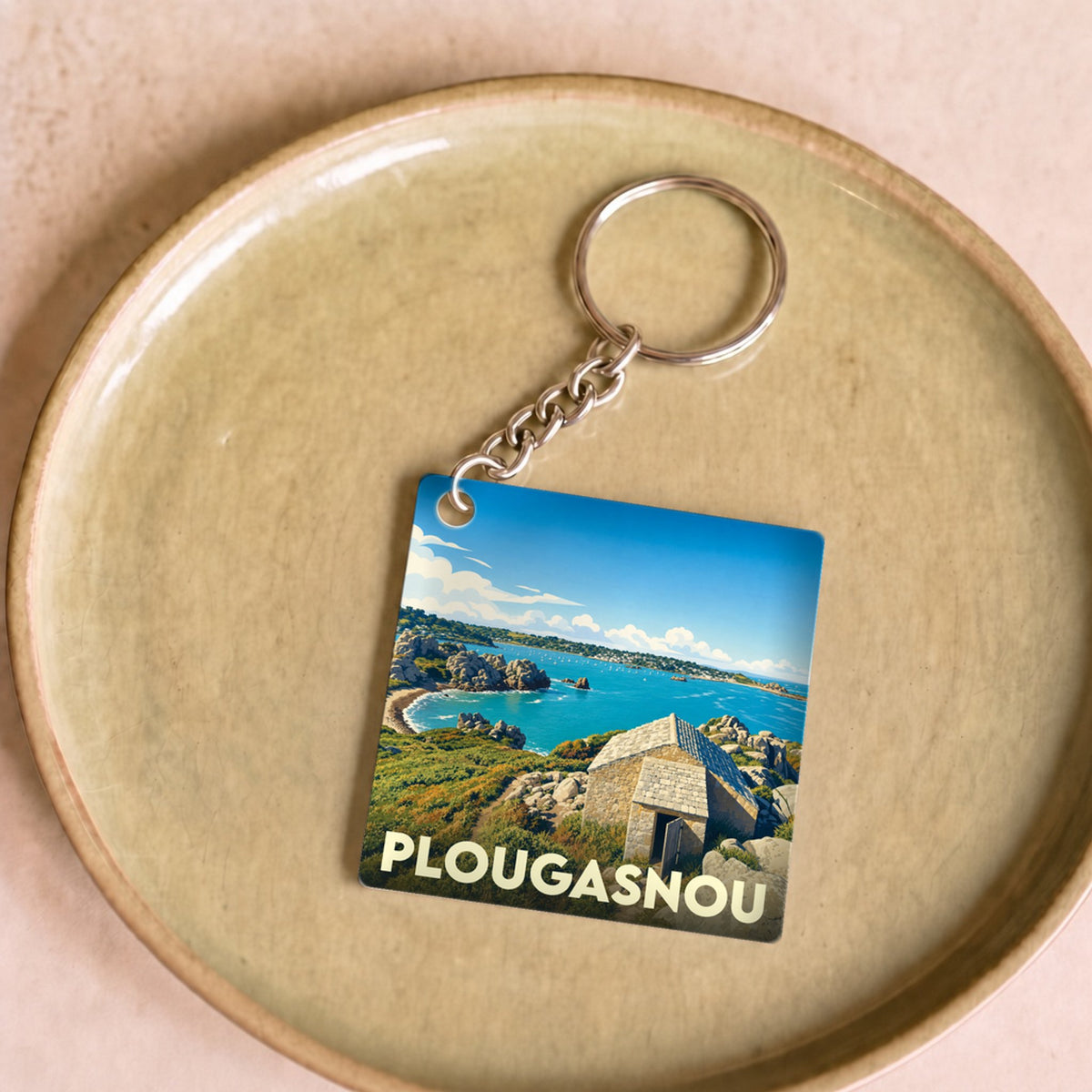 Porte-clés souvenir de la ville de Plougasnou avec une illustration stylisée d'un paysage côtier.