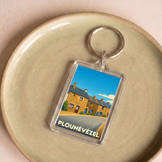 Porte-clés souvenir de la ville de Plounévézel avec une illustration stylisée de maisons traditionnelles.